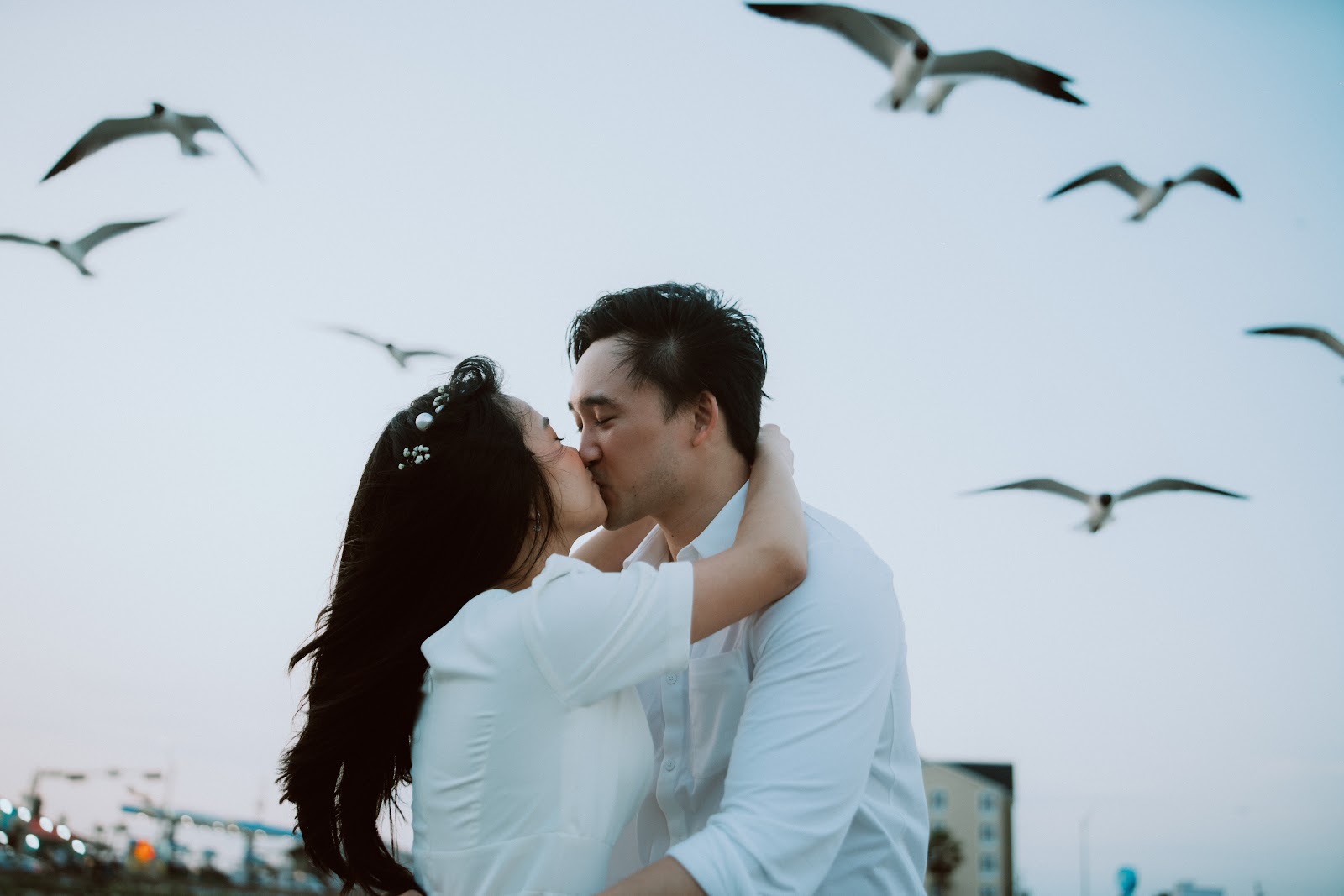 A couple kissing on the beach as seabirds wheel above them