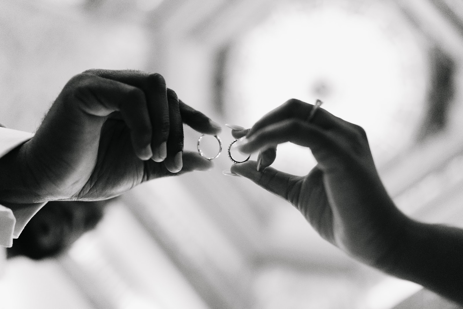 Hands exchanging rings in soft black-and-white focus