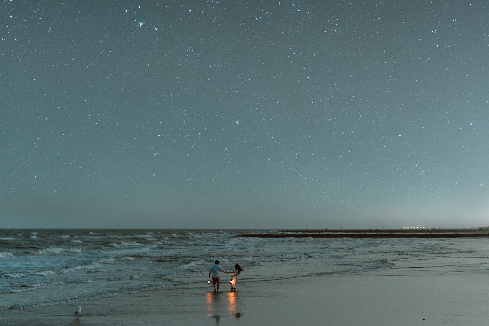 A couple standing close on a darkening beach after their vows