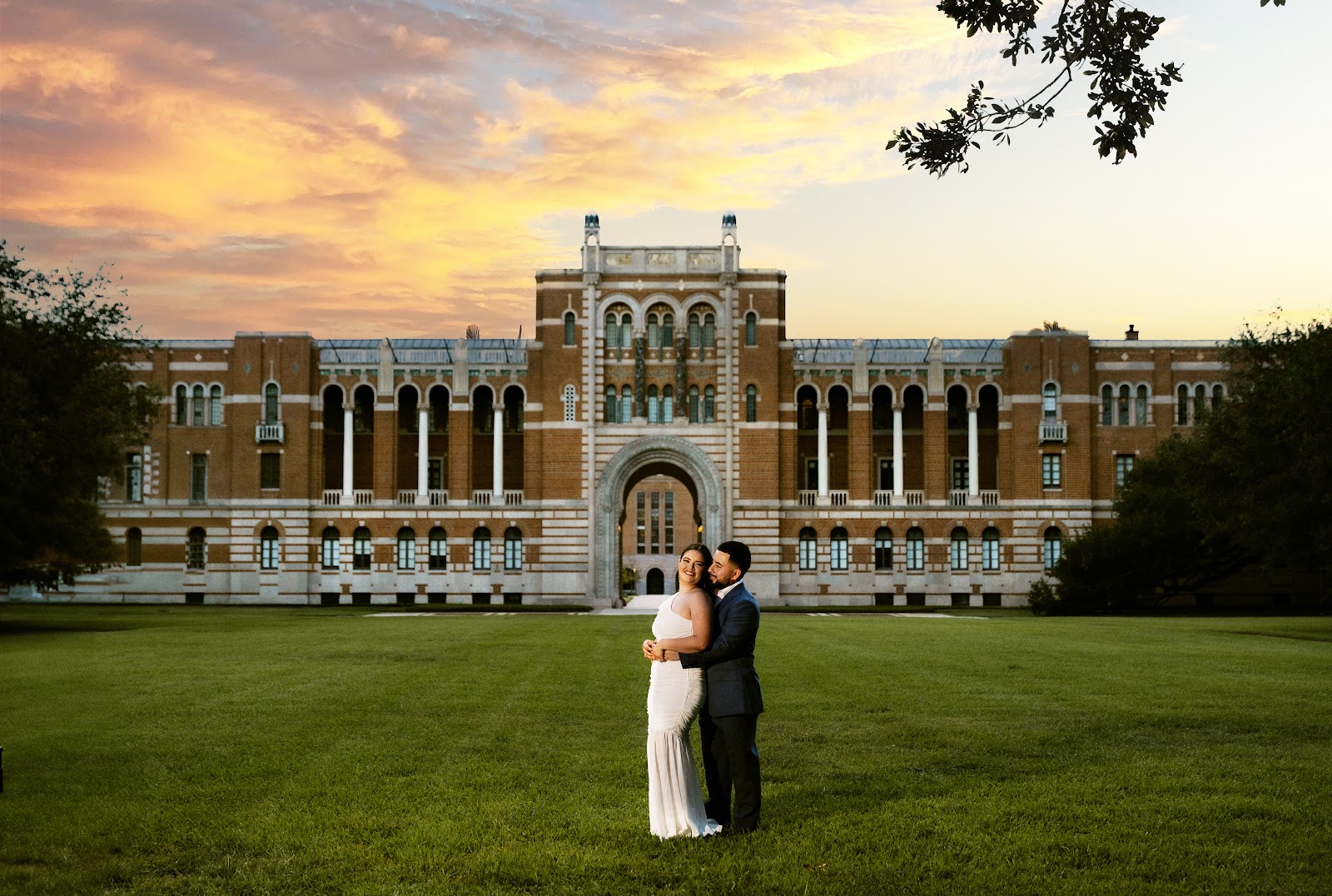A couple standing on a great lawn beneath a golden sunset sky