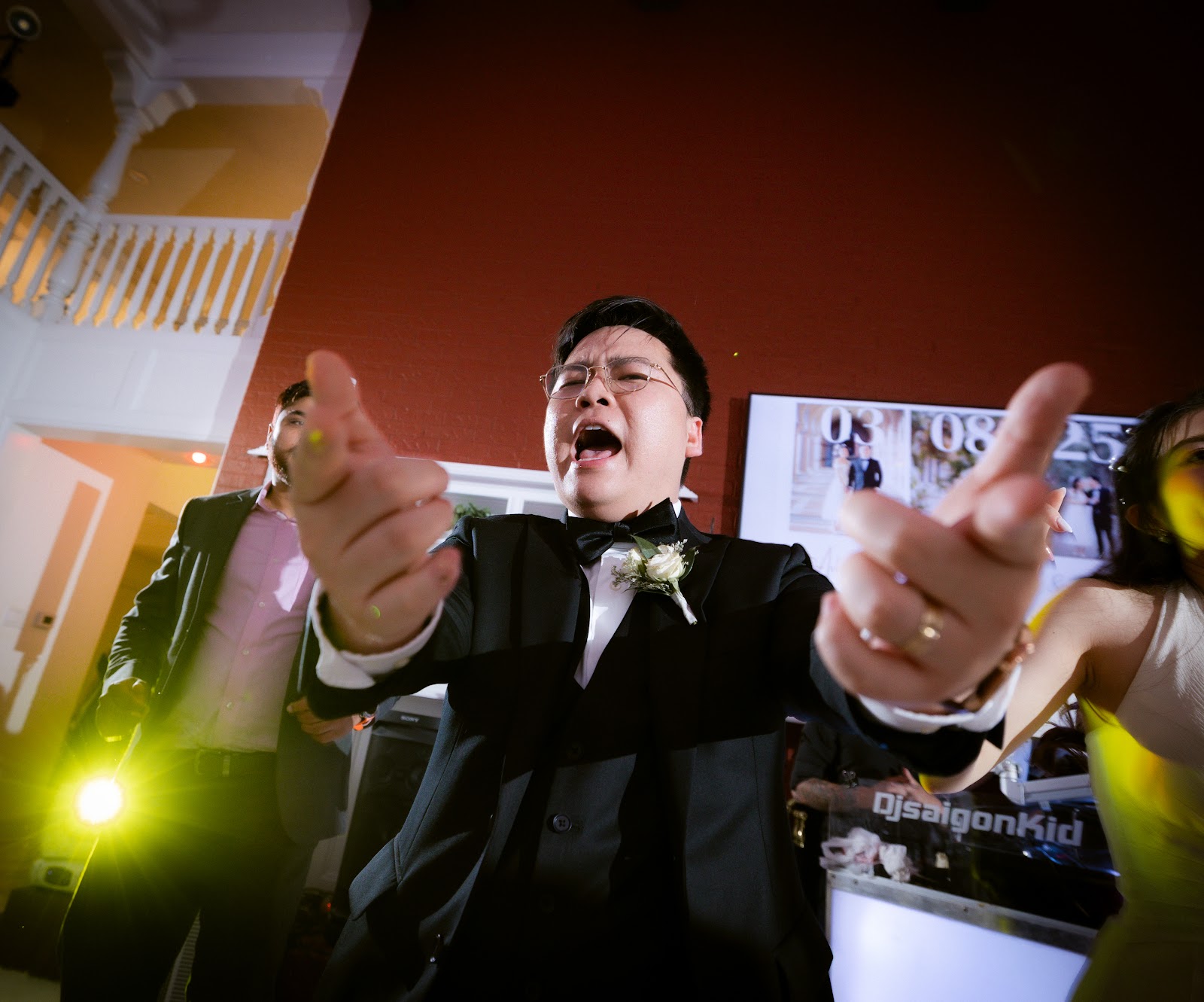 A groom cheering with his arms raised in pure joy