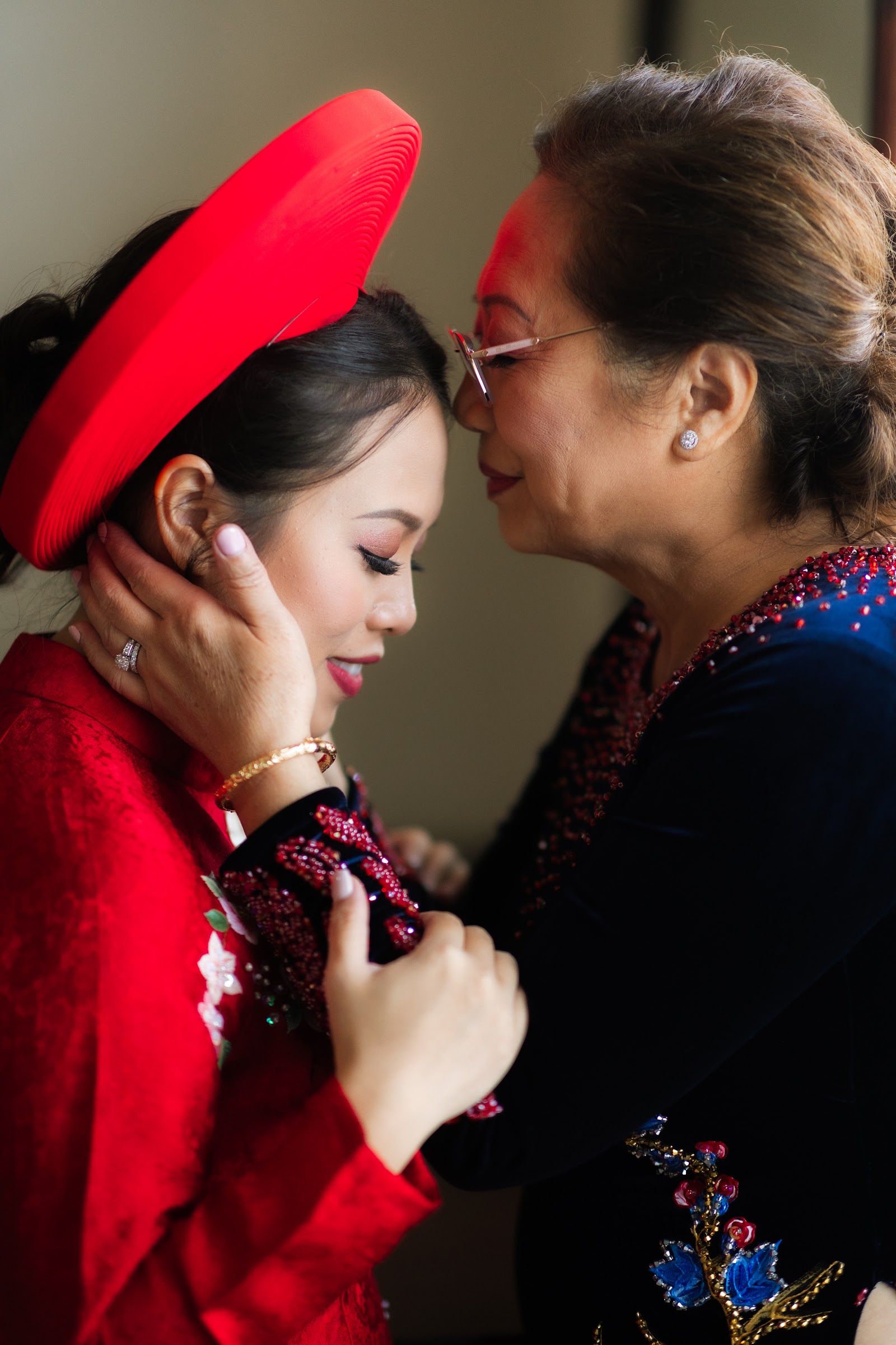 A mother in a red hat touching her daughter's face before the ceremony