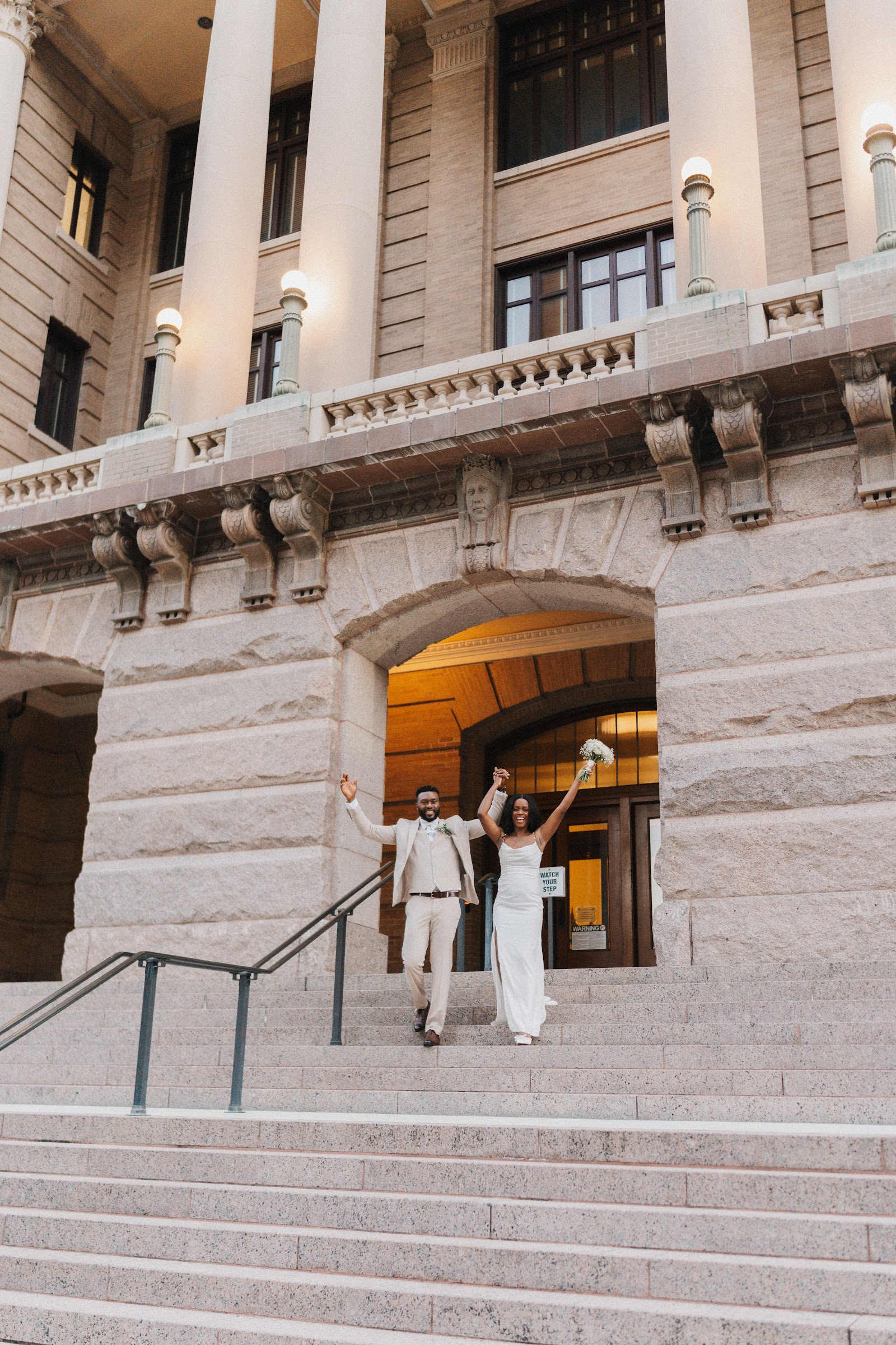 A couple descending the stone steps of a grand mansion
