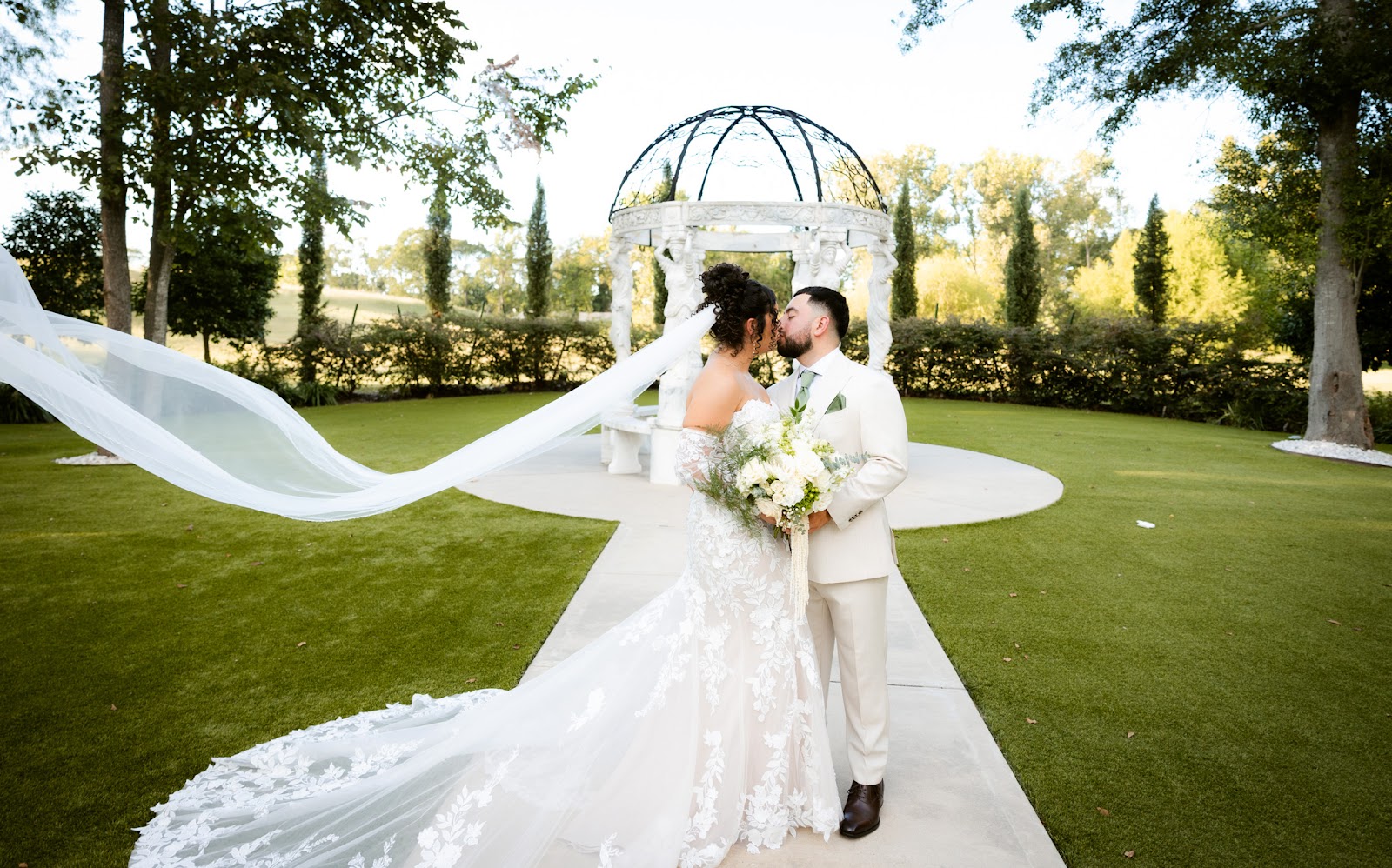 A bride twirling as her veil catches the wind on a wide green lawn